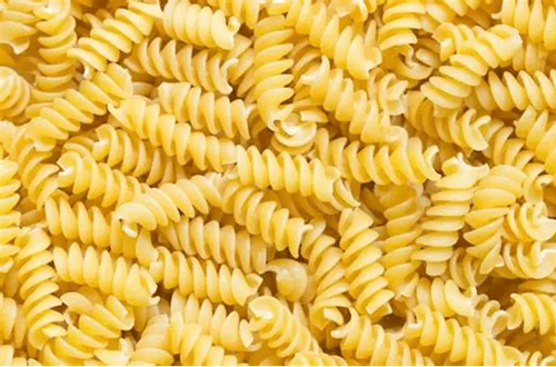 Pasta seca tipo fusilli o espirales de color amarillo intenso, ideales para capturar el sabor de las vinagretas.