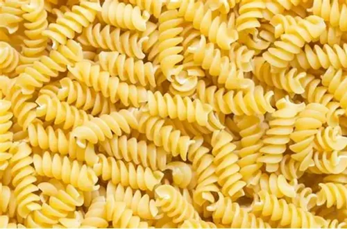 Pasta seca tipo fusilli o espirales de color amarillo intenso, ideales para capturar el sabor de las vinagretas.