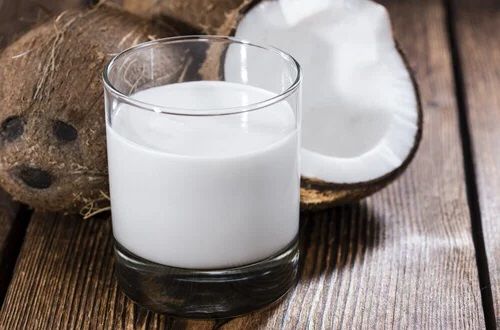 Leche de coco Leche de coco blanca y espesa en un tazón de cristal, el ingrediente clave para la cremosidad de la salsa.