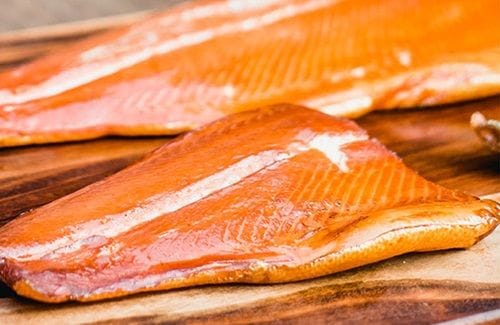 Láminas de salmón ahumado, con un color naranja más intenso y una textura más firme que el fresco.
