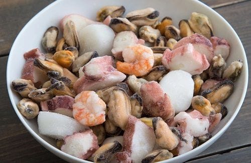 Surtido de mariscos Mezcla de mariscos frescos como choritos, camarones y almejas en un bol, listos para la cocción.