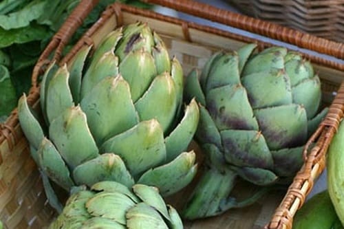 Alcachofas Alcachofas grandes y verdes cortadas por la mitad, listas para ser sumergidas en la olla de cocción.