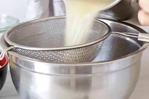 Colador caldo Proceso de filtrado del caldo a través de un colador fino para eliminar restos sólidos y obtener un líquido limpio.
