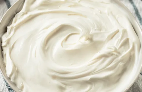 Crema de leche espesa vertiéndose en un bol, lista para ser batida a alta velocidad hasta alcanzar el punto chantilly.