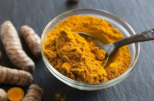 Cúrcuma Polvo de cúrcuma de color naranja intenso en un pequeño plato de cerámica, ingrediente clave de la leche dorada.