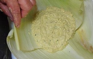 Pasta de choclo (humita) siendo vertida sobre hojas de choclo para el armado.