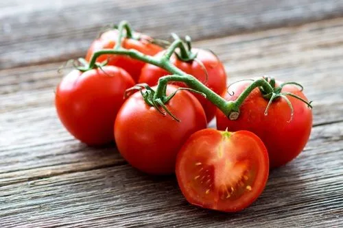 Grupo de tomates cherry rojos, redondos y brillantes, que aportan frescura y color a la ensalada.