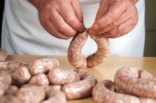 Proceso de embutido de longanizas, mostrando la tripa rellena y torcida en unidades.