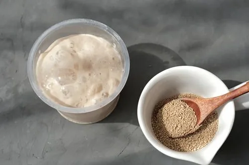 Levadura en polvo disuelta en agua tibia con azúcar, mostrando burbujas de activación.