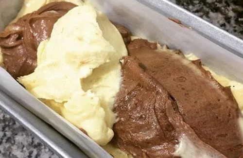 Masa de queque de vainilla y chocolate alternada en un molde, lista para hornear y crear el efecto mármol.