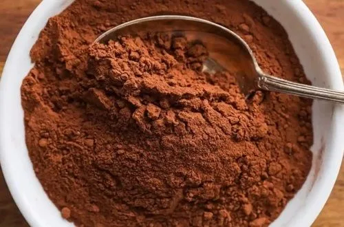 Cacao en polvo sin azúcar en una cuchara. Ingrediente para crear la mitad de chocolate de la masa marmoleada.