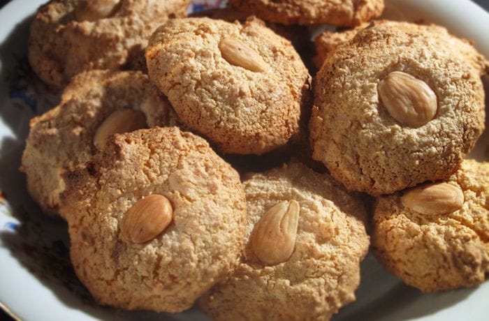 Almendrados redondos rebozados en azúcar flor y coronados con una almendra, listos para hornear.
