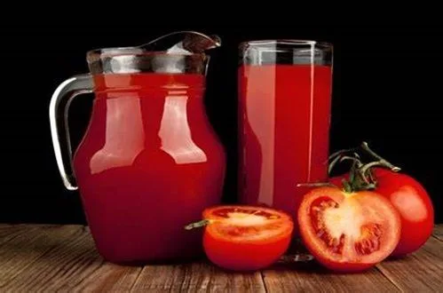 Jugo de tomste Jugo de tomate rojo vibrante siendo vertido en una coctelera para preparar la base del cóctel.