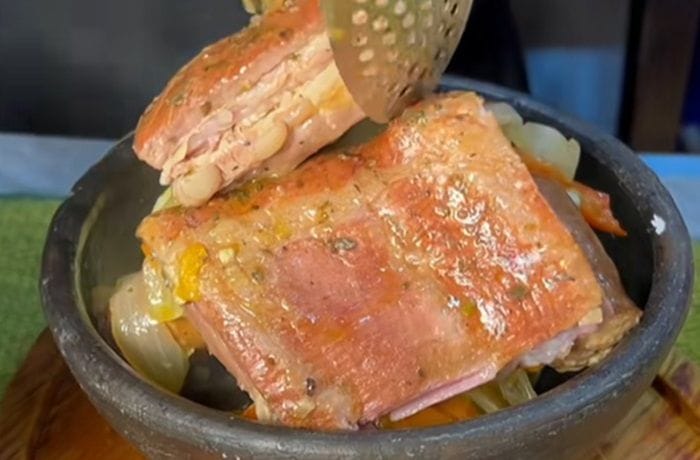 Chancho borracho a la chilena servido en una olla de greda, con costillar de cerdo ahumado, longanizas y repollo.