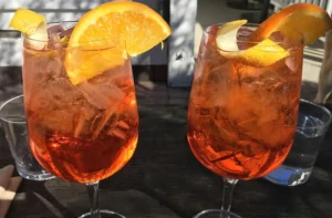 Aperol spritz en copa con hielo y rodaja de naranja, receta del cóctel italiano