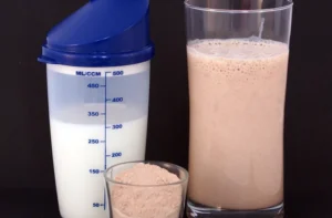 Batido de proteínas casero con plátano y avena en vaso, receta fácil en licuadora