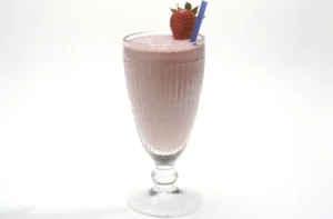 Milkshake casero en vaso alto con crema batida, receta de milkshake con helado