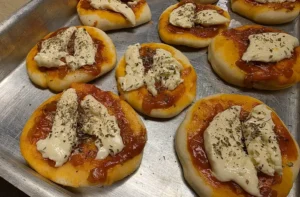Pizzetas caseras con salsa de tomates, queso y orégano, receta para cumpleaños