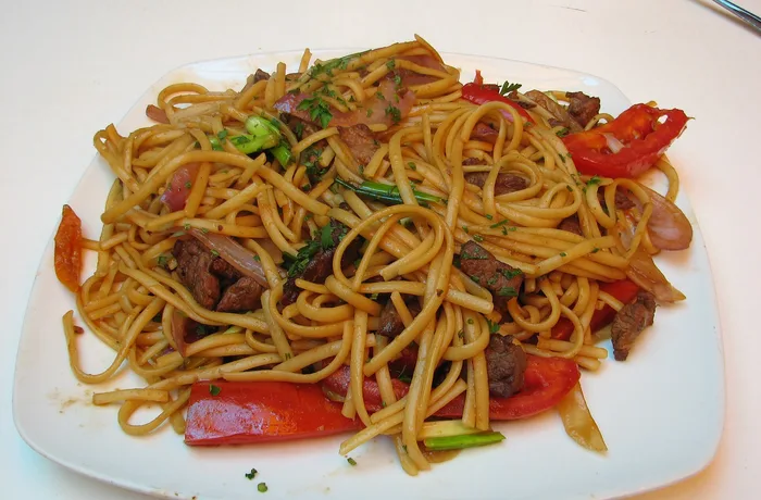 Tallarín saltado de carne con cebolla morada, tomate y cebollín, receta chifa peruana